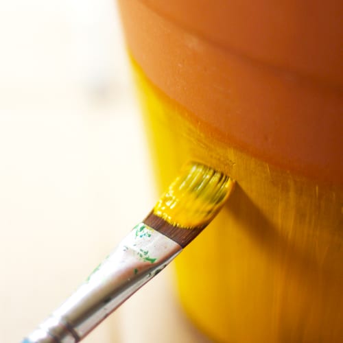 painting yellow paint on pottery