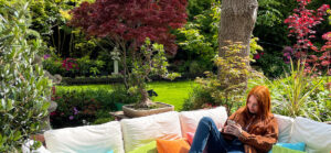 woman looking at phone outside around trees and shrubs