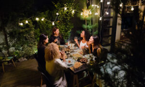 group of friends having dinner outside surrounded by plants